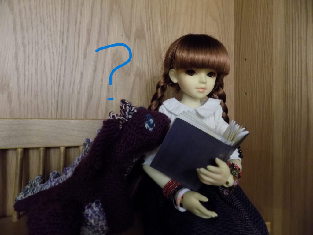 Photo of a doll reading a book on a bench.