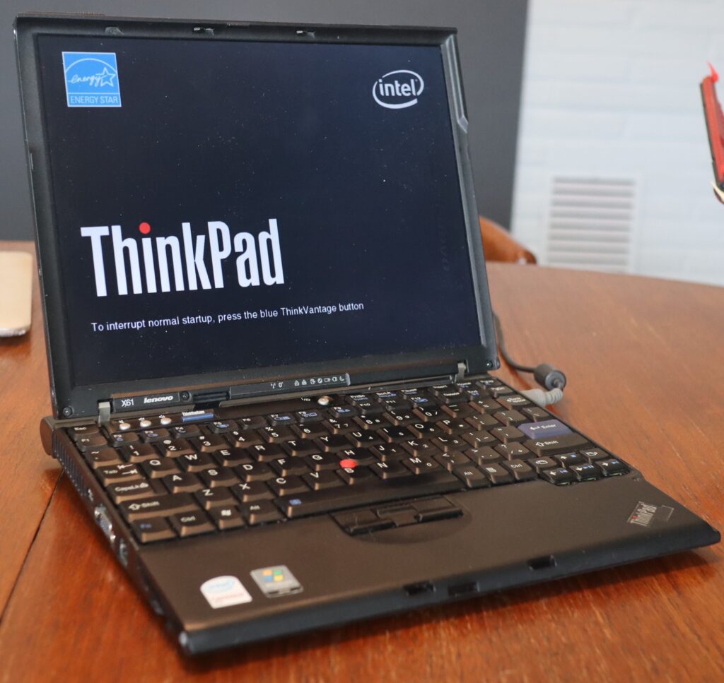 An old Intel ThinkPad in black casing opened to the booting screen.